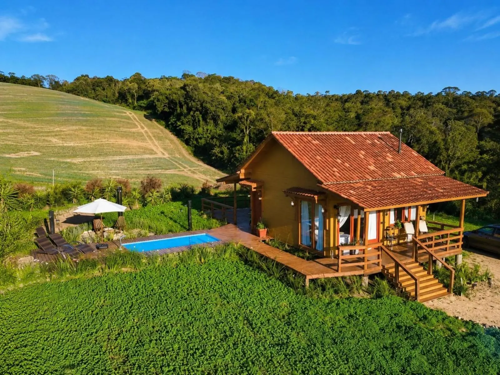 Cabana Gaia no alto do sítio, com a piscina e o morro ao fundo
