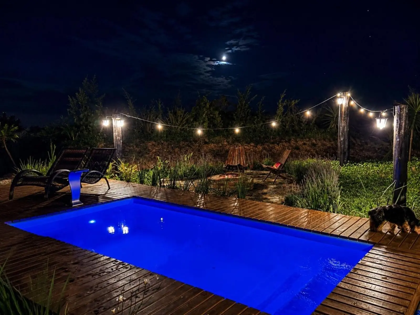 Piscina iluminada à noite, com varal de luzes