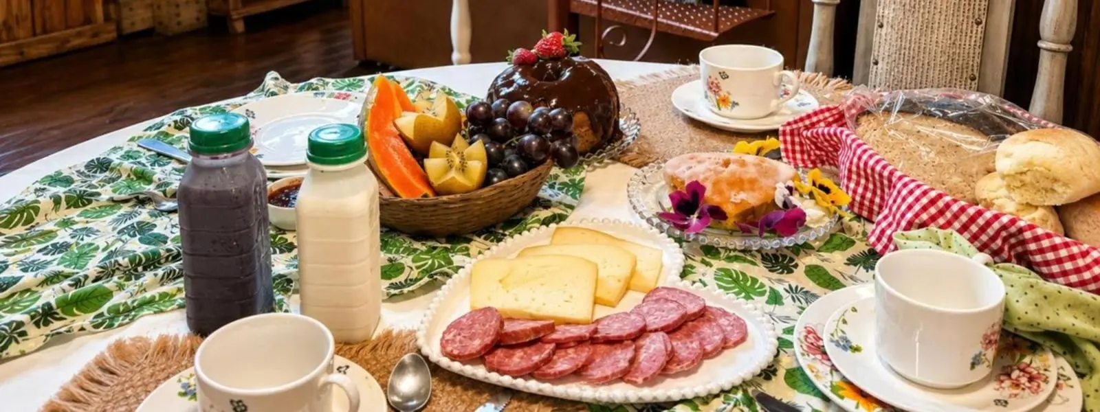 Mesa posta na cabana com queijo, salame, frutas, bolo e pão caseiro