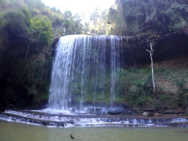 Cachoeira larga caindo sobre degraus de pedra num poço