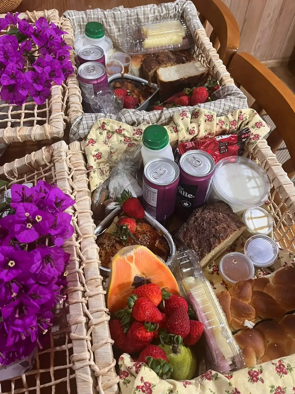 Cesta do café colonial com morangos, mamão, bolo, pães, iogurte e geleias